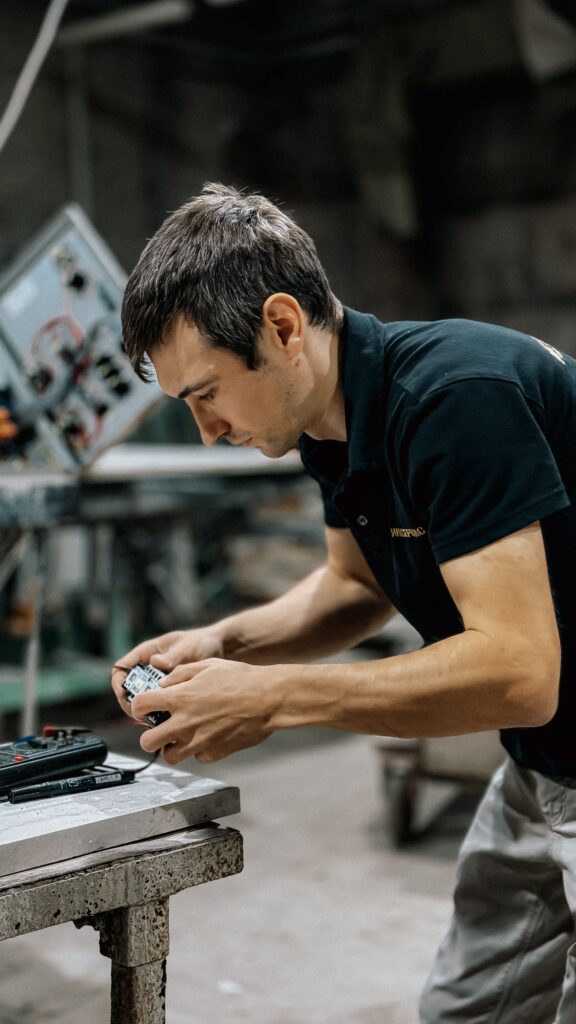 pexels-photo-33694032-33694032 Male technician focusing on electrical component in a workshop setting, showcasing precision and skill.