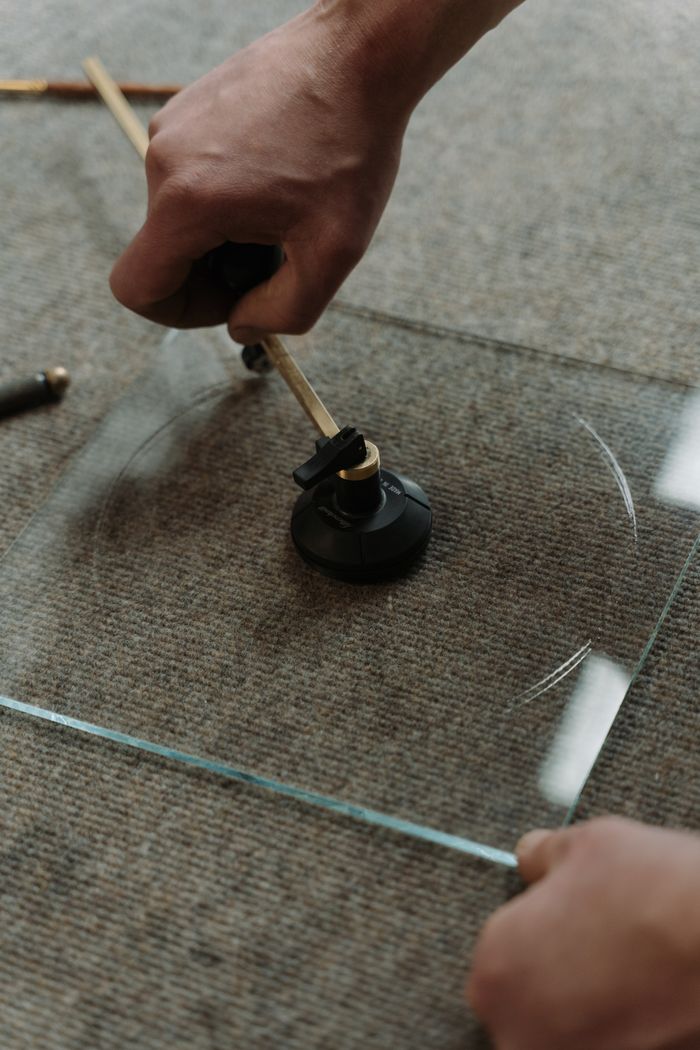 A close-up of an artisan expertly cutting glass with precision tools in a workshop.