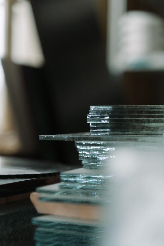 pexels-photo-7219191-7219191 A close-up view of stacked glass sheets indoors, capturing textures and reflections.